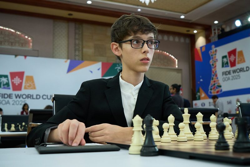 Ilan Schnaider, con anteojos y saco negro, sentado ante el tablero en la Copa del Mundo FIDE de Goa 2025