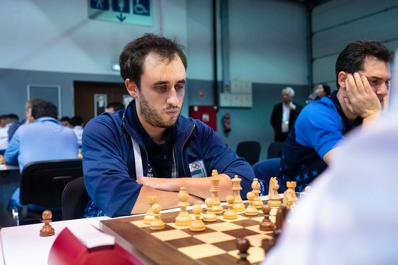 Leandro Krysa, con campera azul del equipo argentino, sentado ante el tablero en la Olimpíada de Budapest 2024