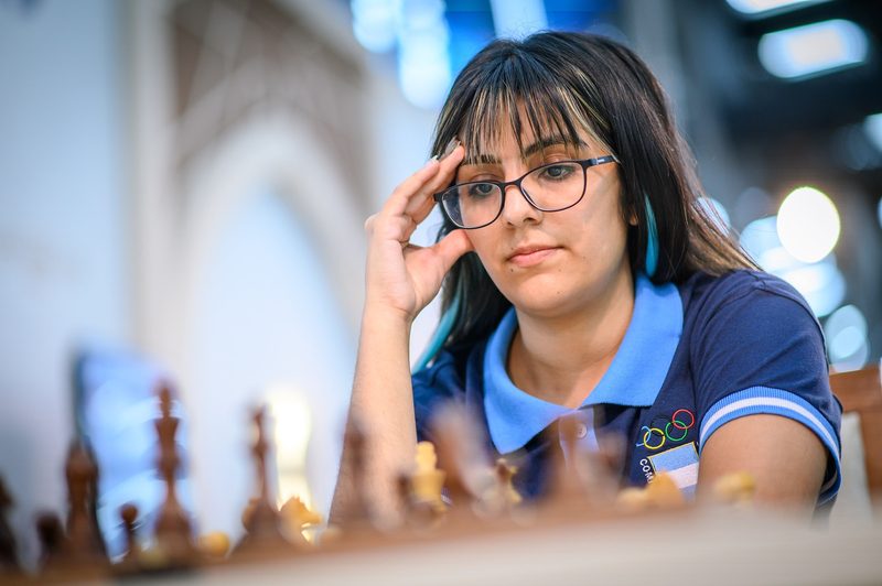 María José Campos, con anteojos y la camiseta celeste y azul de Argentina, concentrada frente al tablero en la Olimpíada de Samarcanda